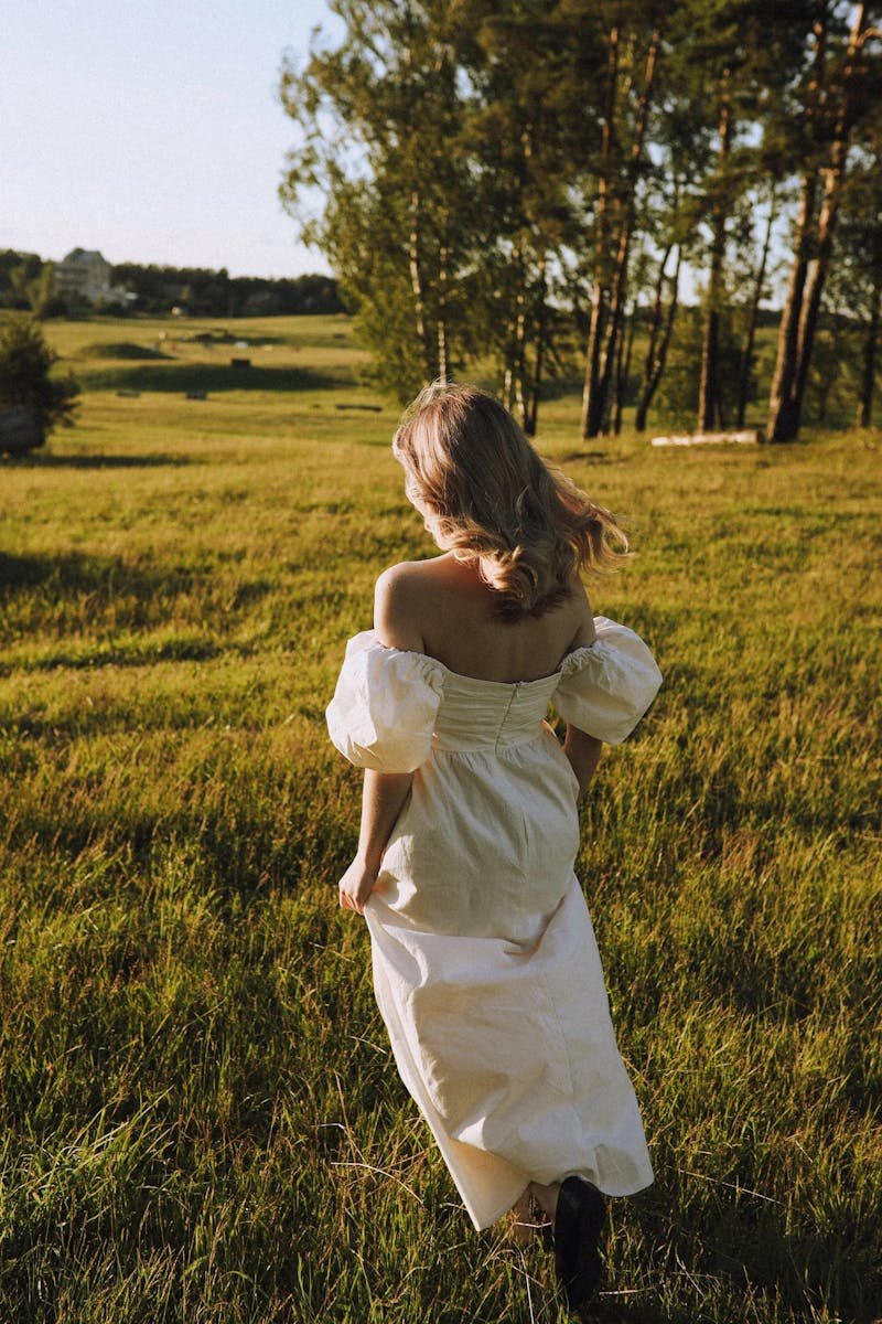 A woman in a white dress walking through a field