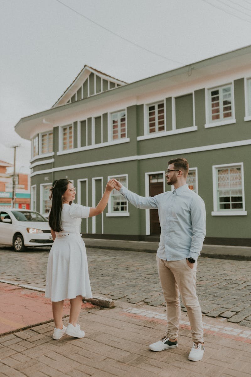 A couple holding hands in front of a green building